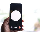 Dłoń trzymająca smartfon z interfejsem asystenta głosowego na ekranie