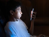 Nastolatek w ciemnym pokoju, wpatrujący się w świecący ekran smartfona