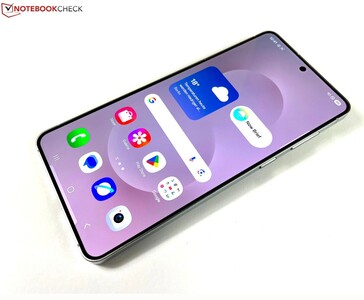 Zbliżenie na Samsung Galaxy S25 Edge pokazujące jego płaski wyświetlacz, cienkie ramki i ekran główny z widocznymi ikonami pogody i aplikacji. (Źródło zdjęcia: Notebookcheck)