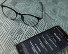 Smartfon z uruchomioną aplikacją ChatGPT obok pary okularów na wzorzystej powierzchni