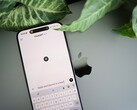 Smartfon z uruchomioną aplikacją ChatGPT, leżący na laptopie obok liści rośliny
