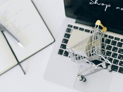 Miniaturowy koszyk na klawiaturze laptopa, z napisem „Kup teraz” na ekranie