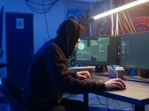 Haker generyczny przy stacji roboczej z dwoma monitorami przeprowadzający atak na łańcuch dostaw.