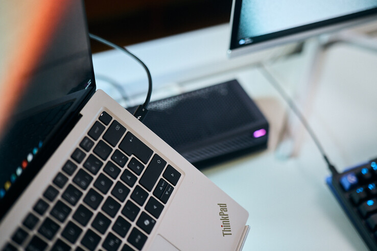 Zbliżenie kabla Thunderbolt 5 podłączonego do bocznego portu laptopa Lenovo ThinkPad X9, z kartą graficzną Aorus eGPU w tle.