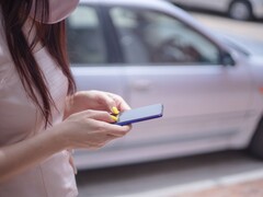 Kobieta pisząca na smartfonie ze srebrnym samochodem w tle