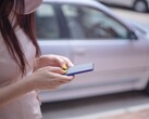 Kobieta pisząca na smartfonie ze srebrnym samochodem w tle
