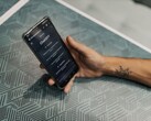 Dłoń trzymająca smartfon z otwartą aplikacją ChatGPT nad wzorzystym stołem