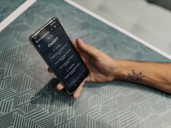 Dłoń trzymająca smartfon z otwartą aplikacją ChatGPT nad wzorzystym stołem