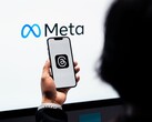 Dłoń trzyma smartfon przed dużym logo Meta