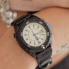 Timex Intrepid x Dimepiece Blackout Edition ma czarną kopertę ze stali nierdzewnej, kremową tarczę i fioletowe akcenty
