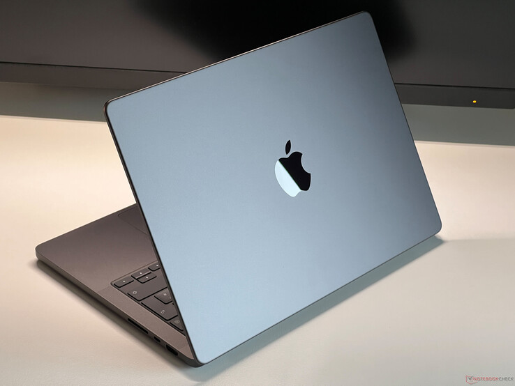 Apple MacBook Pro w kolorze Space Grey umieszczony na biurku z częściowo otwartą pokrywą, pokazujący klawiaturę i logo Apple (źródło obrazu: Notebookcheck)