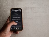 Dłoń trzymająca smartfon z interfejsem ChatGPT na ekranie nad szarą kamienną powierzchnią