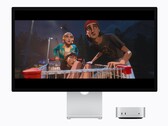 Zdjęcie przedstawia nowy komputer Mac mini M6 obok monitora Studio Display. Odtwarzany jest jakiś film. 