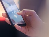 Ręka trzyma smartfon i odblokowuje go za pomocą czytnika linii papilarnych na ekranie blokady.