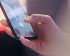 Ręka trzyma smartfon i odblokowuje go za pomocą czytnika linii papilarnych na ekranie blokady.