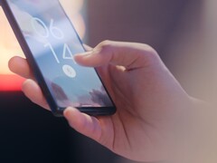 Ręka trzyma smartfon i odblokowuje go za pomocą czytnika linii papilarnych na ekranie blokady.