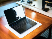 Otwarty, matowo-czarny laptop gamingowy Razer Blade 16 stojący na białej podkładce biurkowej, umieszczonej na ciepłym drewnianym stole, z wyświetlaną na ekranie wyrazistą czarno-białą tapetą.