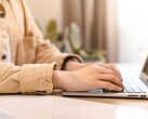 Ręce piszące na klawiaturze otwartego laptopa na jasnym biurku