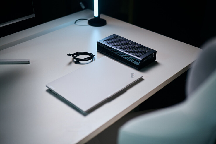 Zamknięty biały laptop ThinkPad stojący obok kompaktowego urządzenia eGPU Aorus RTX 5060 Ti AI Box oraz zwiniętego kabla Thunderbolt na biurku.