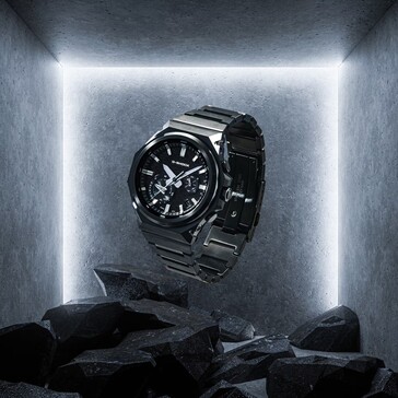 G-Shock GST-B1000BD-1A zawieszony nad ciemnymi skałami w betonowej przestrzeni wystawowej, podkreślający swoją czarną konstrukcję ze stali nierdzewnej.