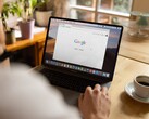 Osoba przy laptopie z otwartą stroną główną Google, obok filiżanki kawy