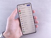 Dłoń trzyma smartfon, na którego ekranie wyświetla się lista aktualizacji.