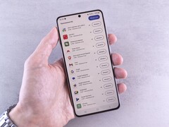 Dłoń trzyma smartfon, na którego ekranie wyświetla się lista aktualizacji.