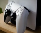 Zdjęcie kontrolera PlayStation 5 DualSense opartego o konsolę PS5