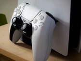 Zdjęcie kontrolera PlayStation 5 DualSense opartego o konsolę PS5