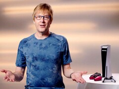  Mark Cerny podczas wydarzenia PlayStation, siedzący obok konsoli PS5 i kontrolerów DualSense. (Źródło obrazu: Sony Interactive Entertainment)