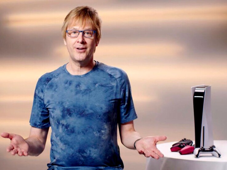 Mark Cerny podczas wydarzenia PlayStation, siedzący obok konsoli PS5 i kontrolerów DualSense. (Źródło obrazu: Sony Interactive Entertainment)