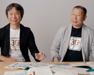 Zrzut ekranu przedstawiający Shigru Miyamoto i Tezukę Takashiego w koszulkach z okazji 30-lecia Super Mario Bros