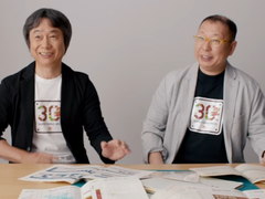 Zrzut ekranu przedstawiający Shigru Miyamoto i Tezukę Takashiego w koszulkach z okazji 30-lecia Super Mario Bros