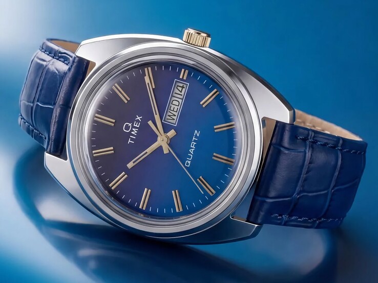 Ujęcie zegarka Timex Q 1976 Day and Date pod kątem, podkreślające jego niebieską tarczę z gradientem, polerowaną kopertę ze stali nierdzewnej i koronkę w złotym kolorze.