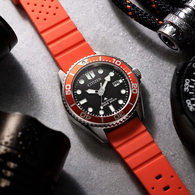 Zegarek nurkowy Citizen Promaster Marine BN0268-01E z czarną tarczą, pomarańczową ramką i pomarańczowym paskiem, sfotografowany na teksturowanej powierzchni.