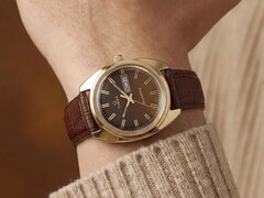 Timex Q 1978 Day and Date z brązową tarczą fumé i kopertą w złotym kolorze, pokazany na nadgarstku z brązowym skórzanym paskiem.