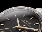 Zbliżenie na zegarek Timex Waterbury Heritage Automatic z czarną tarczą, ukazujące jego fasetowane, luminescencyjne wskazówki, znaczniki godzin, wyświetlacz dnia i daty oraz czarną ramkę.