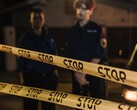 Dwóch policjantów stojących nocą za żółtą taśmą z napisem Stop