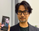 Hideo Kojima pokazujący plakat Physint na swoim telefonie