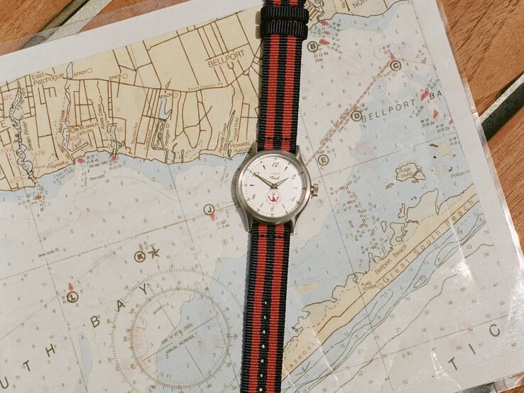 Zegarek Noah x Timex MK1 Anchor z paskiem z tkaniny w granatowo-czerwone paski, leżący na mapie morskiej.