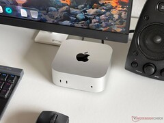 Komputer Apple M6 Mac mini na biurku w zestawie do gier wraz z monitorem, klawiaturą, myszą i głośnikiem.