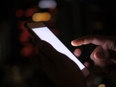 Ręka trzymająca smartfon z podświetlonym ekranem w ciemności