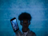 Unoszący się smartfon z kodem na ekranie na niebieskim tle, z rozmytą postacią w tle