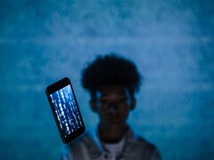 Unoszący się smartfon z kodem na ekranie na niebieskim tle, z rozmytą postacią w tle