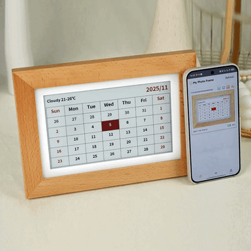 Cyfrowa ramka na zdjęcia Bigme wyświetlająca kalendarz obok smartfona.