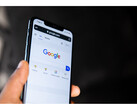 Zdjęcie dłoni trzymającej smartfon z otwartą na ekranie stroną główną wyszukiwarki Google. (Źródło zdjęcia: Solen Feyissa na Flickr)