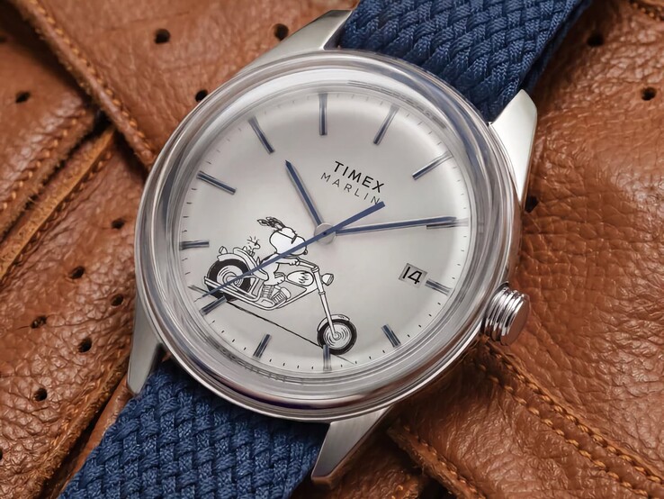 Widok z przodu pod kątem zegarka Peanuts x Timex Marlin Jet Automatic Easy Rider, na którym widoczne są wypukłe szkło, srebrna koperta ze stali nierdzewnej, tarcza z motywem Snoopy’ego oraz niebieski pasek z tkaniny.
