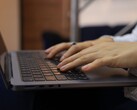 Ręce piszące na klawiaturze ciemnego laptopa