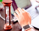 Klepsydra obok dłoni na klawiaturze laptopa