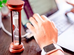Klepsydra obok dłoni na klawiaturze laptopa